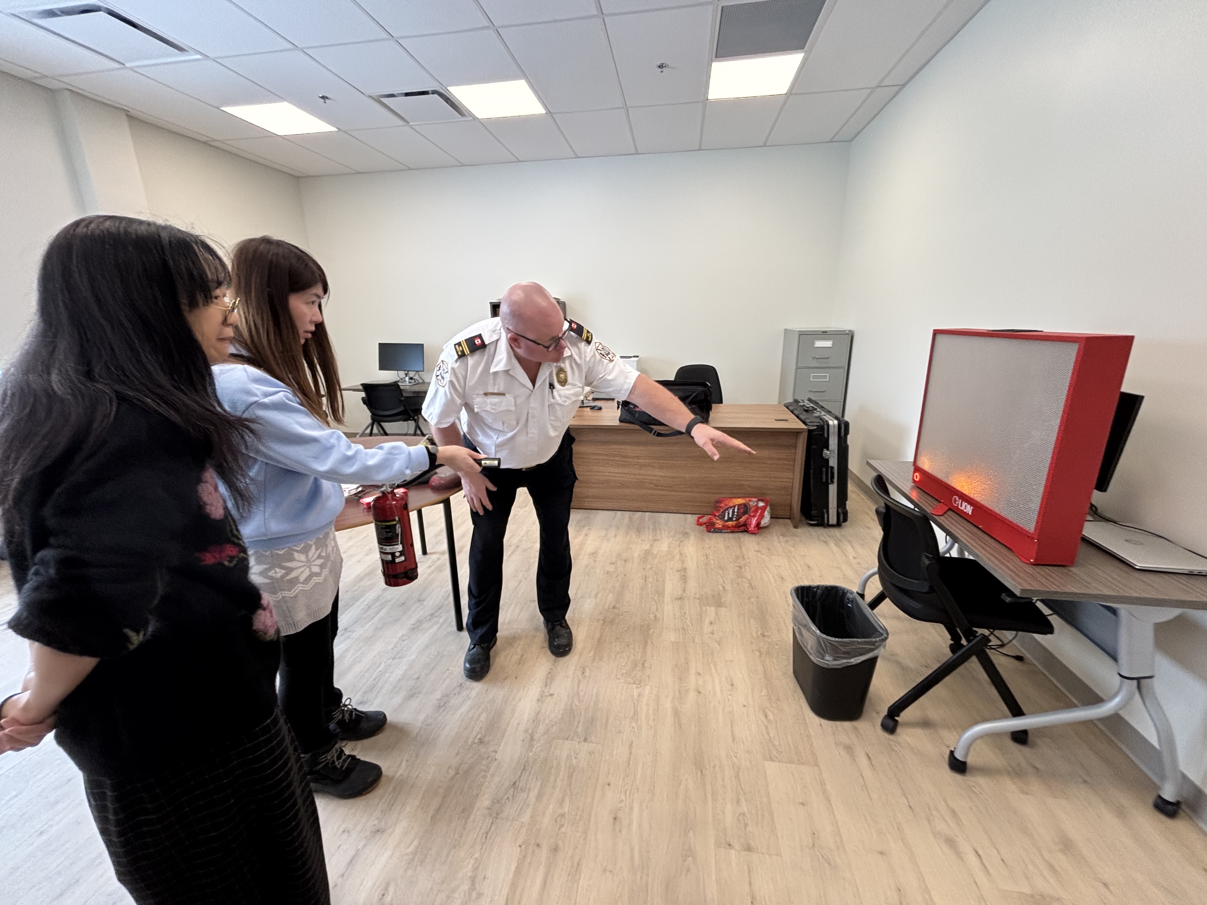 Students Hong & Yuka learn about 911 services and how to properly use a fire extinguisher from Charlottetown Fire inspector, Winston Bryan.