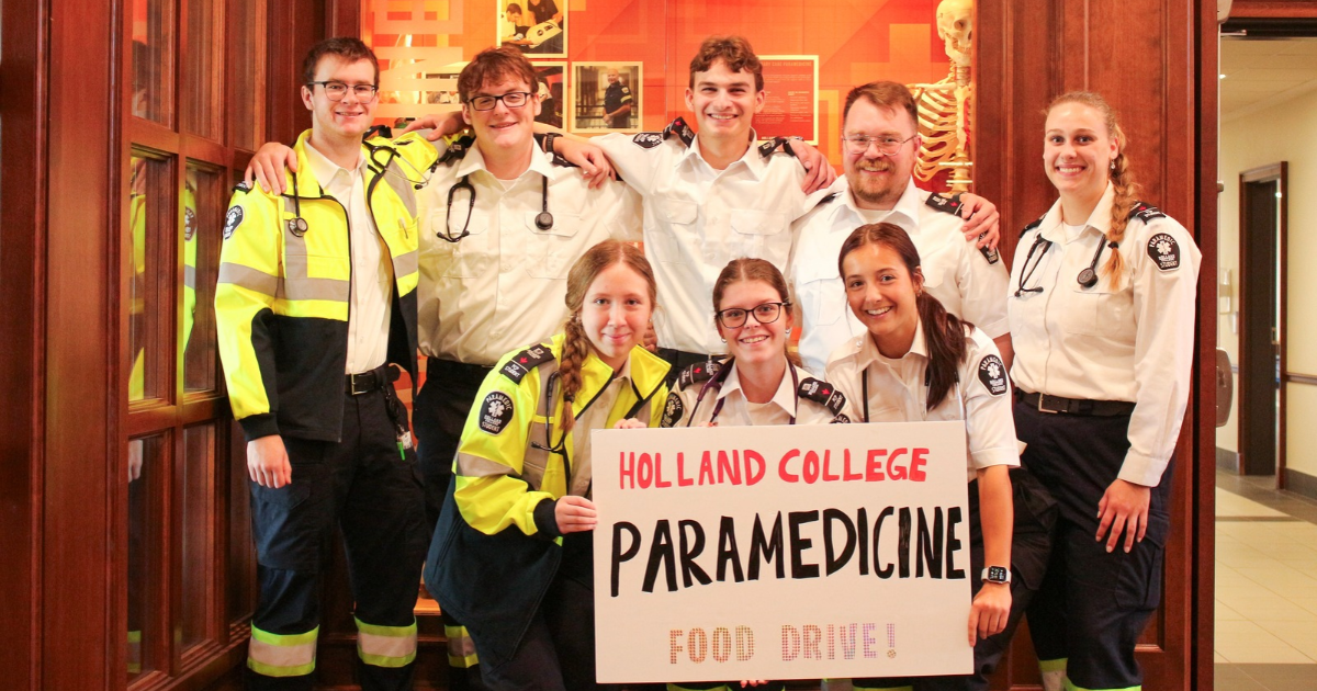A group of Paramedicine students pose with a sign they prepared to advertise the food drive