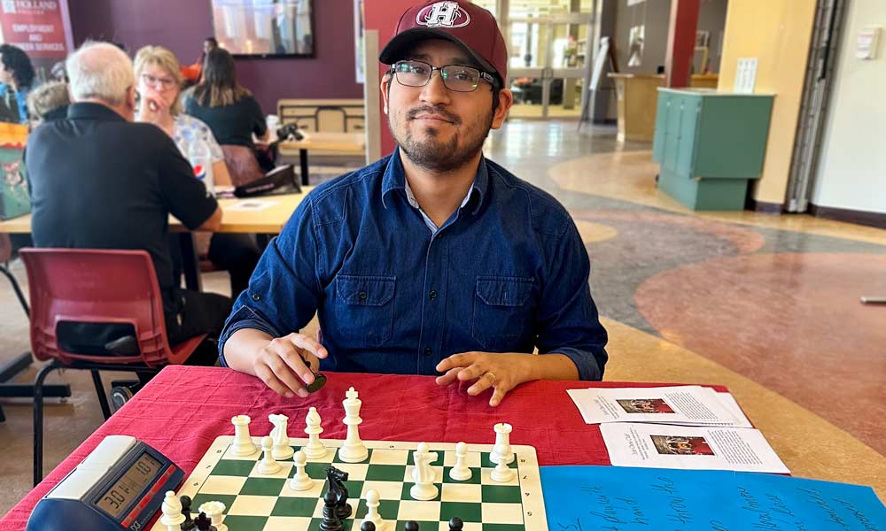 Jorge smiles behind a chess board in the Charlottetown Centre cafeteria.